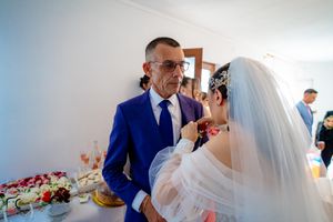 Wedding celebration scene with veil and formal attire in bright interior setting.
