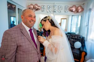 Intimate wedding moment captured in a room decorated with heart-shaped balloons and white curtains.