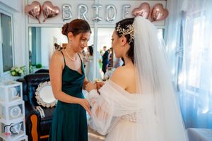 Wedding party gathering in a decorated room with 'BRIDE' balloons and white curtains.