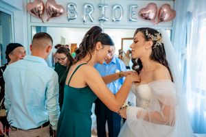 Wedding celebration in a blue-tinted room with rose gold BRIDE balloons and guests mingling.
