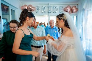 Wedding party gathering under rose gold balloon decorations in a light blue room.