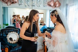 Wedding party members celebrating under rose gold BRIDE balloon decorations.