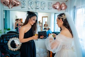 Wedding preparations in a room decorated with rose gold balloons and 'BRIDE' lettering.
