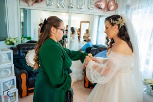 Final wedding dress adjustments in a room with rose gold balloon decorations.