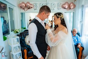 Intimate wedding moment in a room with rose gold heart balloons and 'BRIDE' decor.