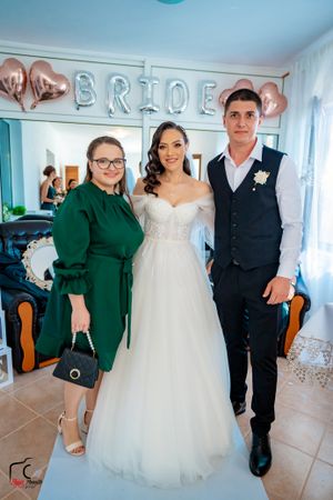 Wedding party photo in a room with rose gold balloon decor and 'BRIDE' lettering.