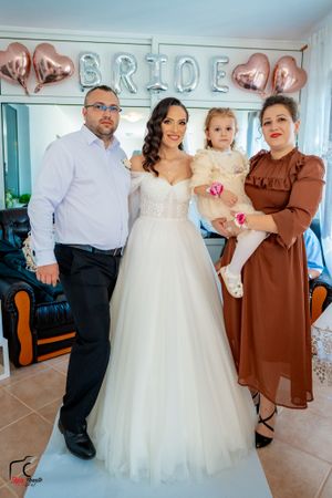 Family portrait at wedding with rose gold balloon decorations and white dress.