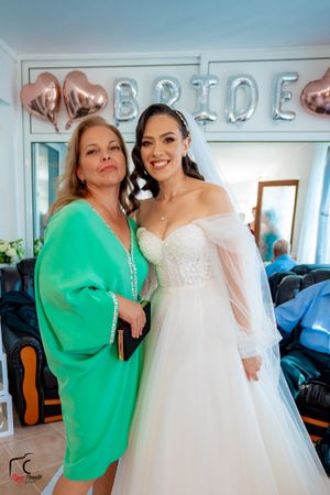 Celebratory moment at a wedding with a bride in white dress and guest in bright green sweater.