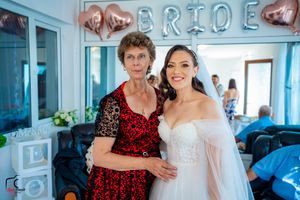 Wedding guests posing together under rose gold balloon decorations in a light-filled room.