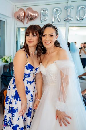 Wedding celebration with guests in blue floral dresses posing under metallic balloon decor.