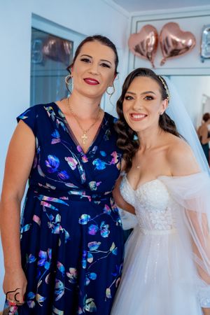 Wedding party member in navy floral dress poses with bride in white gown.