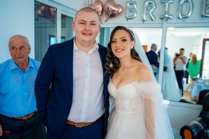 Wedding celebration with guests in formal attire gathered in a bright indoor space.