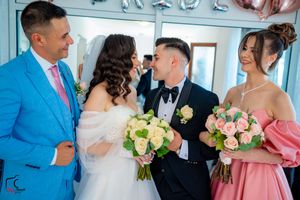 Wedding party gathering in formal attire with pink and white floral bouquets.