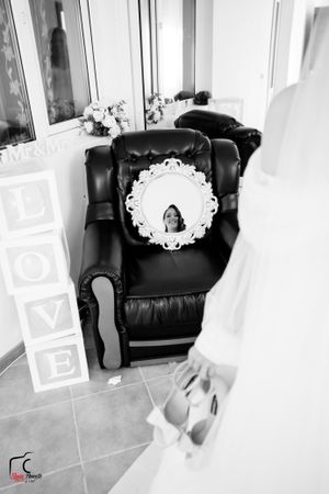 Black and white photo of wedding details with LOVE blocks and ornate mirror on leather chair.