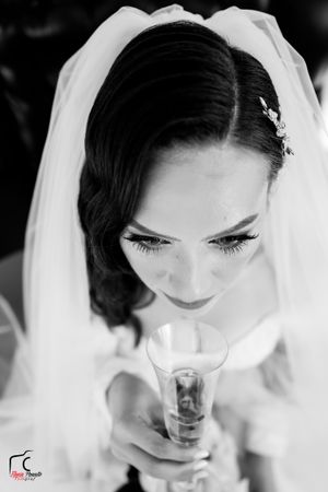 Dramatic black and white portrait of a bride with long lashes looking down at her champagne glass.