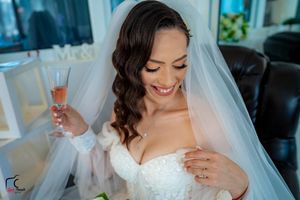 Candid moment of a bride in white dress laughing while holding champagne.