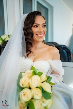 Bride holding pale yellow rose bouquet in natural light with romantic styling.
