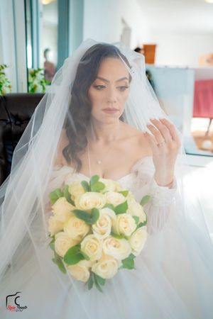 Dreamy bridal portraits through sheer veil with cream rose bouquet in natural window light.