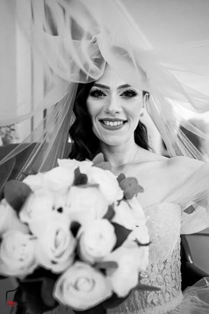 Black and white bridal portrait with flowing veil and white rose bouquet.