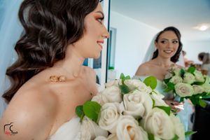 A bouquet of white roses is held while looking in a mirror on the wedding day.