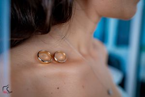 Two gold wedding rings placed artistically on bare skin with a blue background.