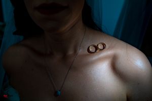 Two wedding rings rest on a shoulder with a delicate necklace visible.