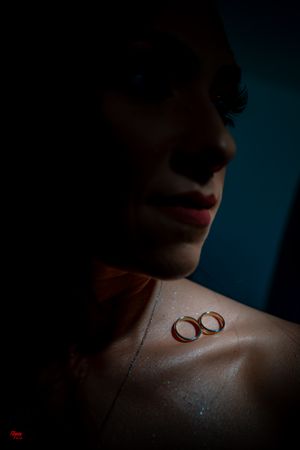 Wedding bands arranged on skin with artistic shadows and teal background.