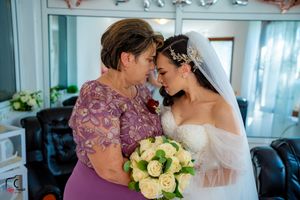 An intimate wedding moment with two people embracing while holding a bouquet of pale yellow roses.
