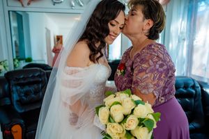 An emotional wedding scene with two people embracing while holding a bouquet of cream-colored roses.