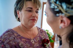Wedding party members share emotional moments in a room decorated with light blue walls and BRIDE lettering.
