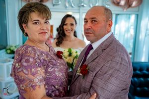 Wedding party members share candid moments in a blue room with decorative wall lettering.