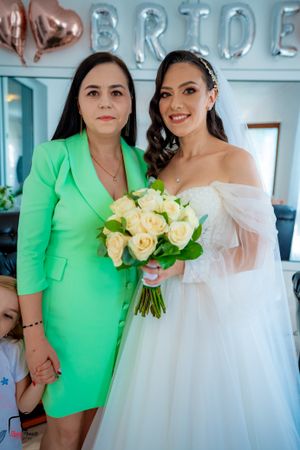 Bride in white tulle gown poses with guest in bright lime green outfit.