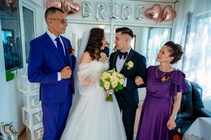 Wedding celebration with guests in formal attire posing together under decorative balloon letters.