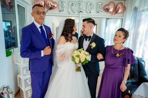 Group photo at wedding reception with bride in white gown and guests in purple and blue attire.