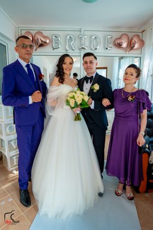 Wedding party members pose together in a bright room with balloon decorations.