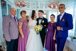 Wedding party photo showing mix of formal attire and decorative balloon backdrop.