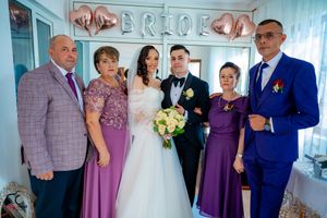 Wedding party poses together in a room decorated with silver balloons and lettering.