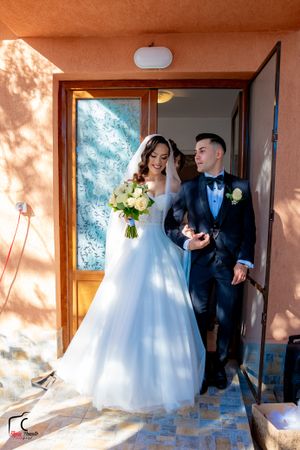 Couple emerges from doorway during wedding ceremony at terracotta-colored venue.