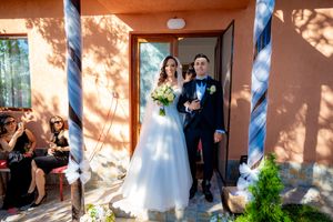 Newlyweds exit through doorway with blue pillars and terracotta walls.