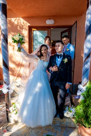 Wedding party poses in doorway of Mediterranean-style building.