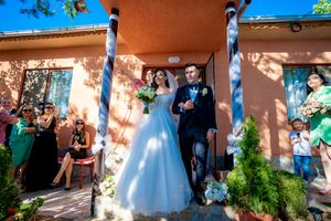 Wedding party and guests celebrating outside a Spanish-style building with terra cotta walls.