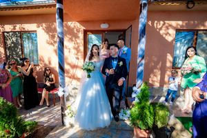 Wedding party celebrating with bubbles and decorations against a peachy-orange building exterior.