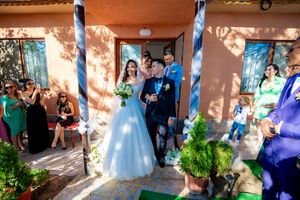 Wedding celebration with guests releasing bubbles outside a Mediterranean-style building.