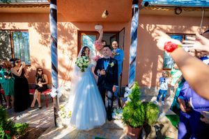 Wedding celebration with white balloons and decorations against an orange stucco wall.
