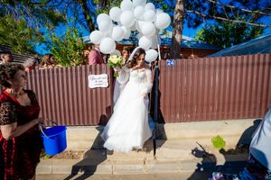 White balloon arch and wedding decorations against bright blue sky at outdoor celebration.