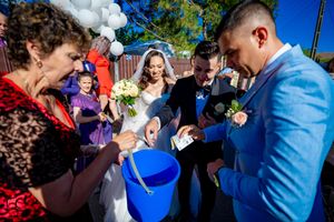 Wedding celebration participants gather around a blue bucket during an outdoor ceremony.