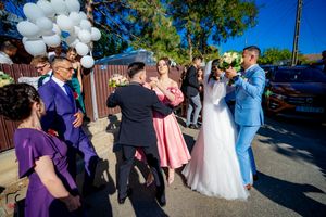 Festive outdoor wedding scene with guests dancing and white balloon decorations.