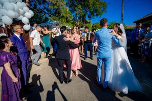Wedding party and guests dancing together at an outdoor celebration with white balloons.