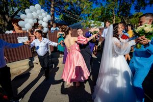 Joyful wedding celebration with guests dancing outdoors under white balloon decorations.