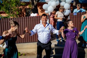 Wedding guests dancing enthusiastically at an outdoor reception with balloon decorations.